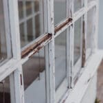 Peeling paint and deteriorating wood trim on an exterior window frame showing early signs of wood rot.